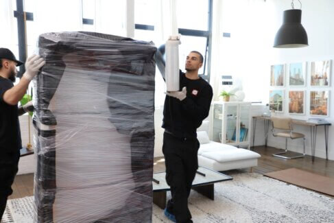 FlatRate movers wrapping a sofa