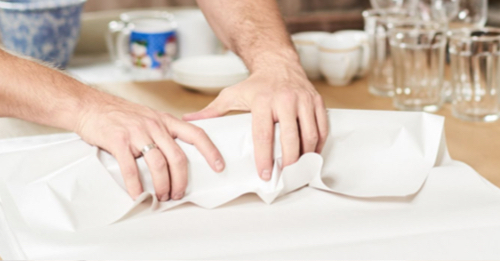 A person wraps some cutlery